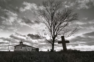 A tree and cross in the middle of nowhere.
