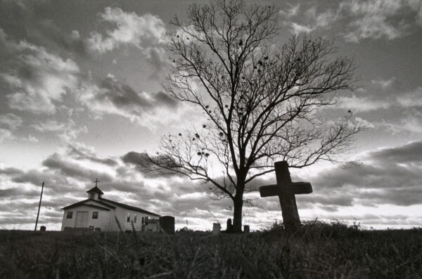A tree and cross in the middle of nowhere.