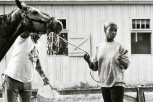 A woman holding onto the reins of a horse