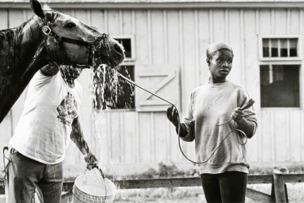 A woman holding onto the reins of a horse