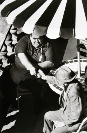 A man and boy are sitting under an umbrella.