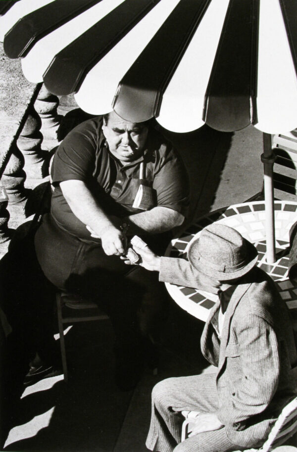 A man and boy are sitting under an umbrella.