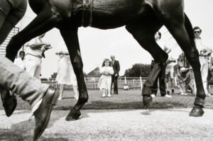 A black and white photo of people standing around horses.