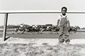A young boy standing in front of a fence.