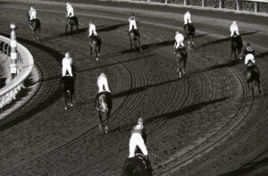 A group of people riding horses on top of a dirt field.