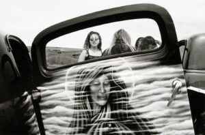 A woman 's reflection in the rear view mirror of a car.