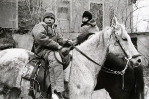 Two people on horseback in a black and white photo.