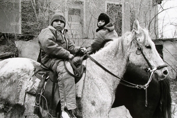 Two people on horseback in a black and white photo.