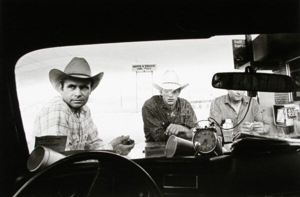 Three men in cowboy hats sitting inside a vehicle.