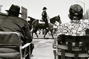 A man on horseback riding down the street.
