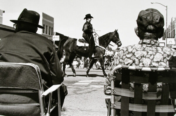 A man on horseback riding down the street.