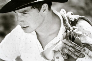 A man in a cowboy hat holding some plants.