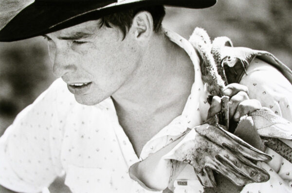 A man in a cowboy hat holding some plants.