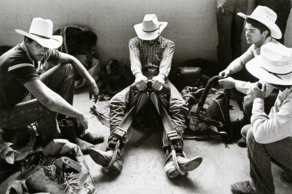 A man sitting on the ground with his hands in his pockets.