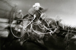 A blurry picture of horses and riders in motion.