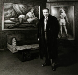 A man standing in front of two paintings.