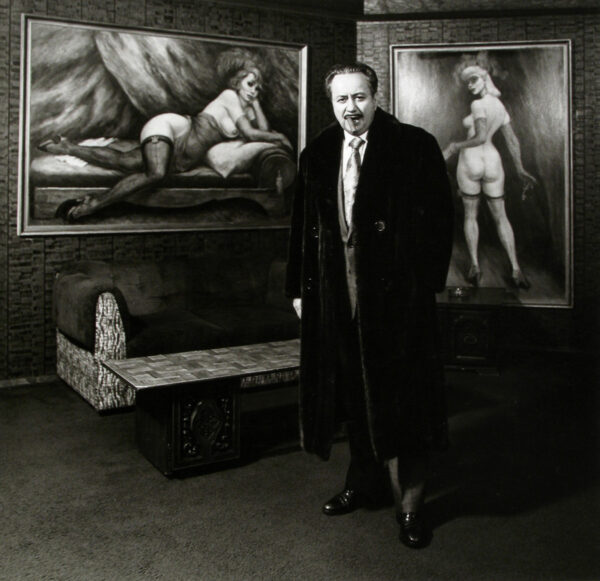 A man standing in front of two paintings.