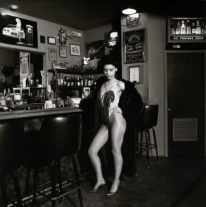 A naked woman standing in front of a bar.