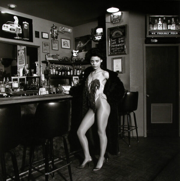 A naked woman standing in front of a bar.
