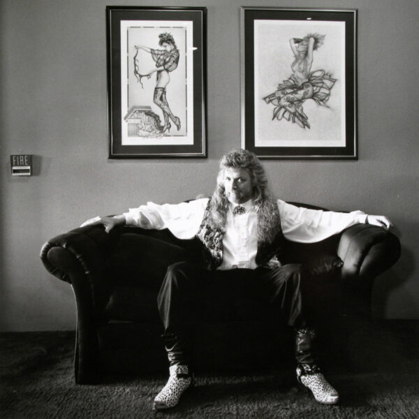 A man sitting on top of a couch in front of two framed pictures.