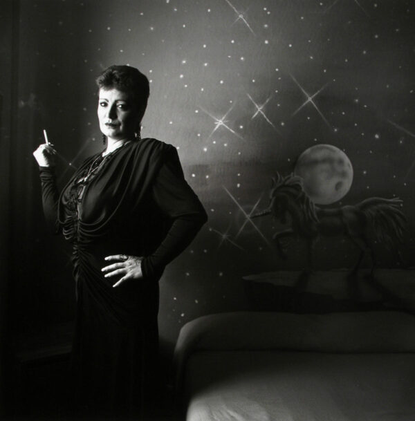 A woman standing in front of a wall with stars and moon.