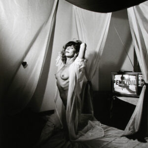 A woman in a white robe standing next to a tv.