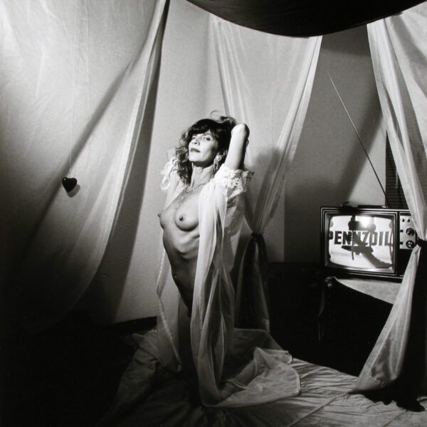 A woman in a white robe standing next to a tv.