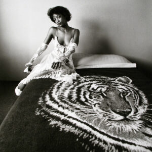 A woman sitting on top of a bed next to a tiger.