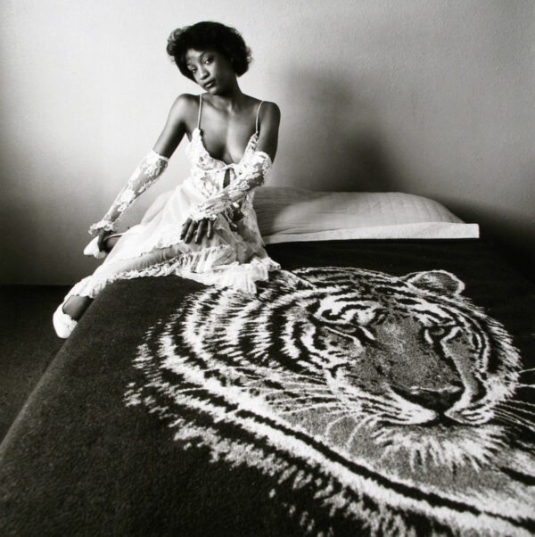 A woman sitting on top of a bed next to a tiger.