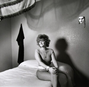 A woman sitting on top of a bed in front of a wall.