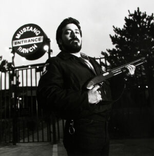 A man holding an automatic rifle in front of a sign.