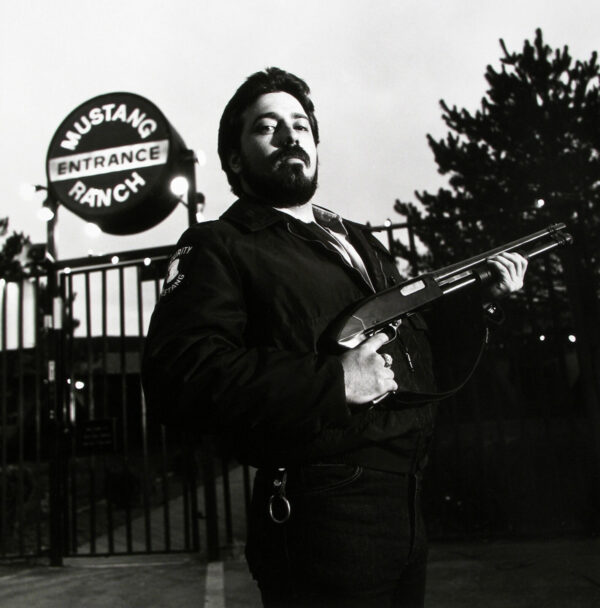 A man holding an automatic rifle in front of a sign.