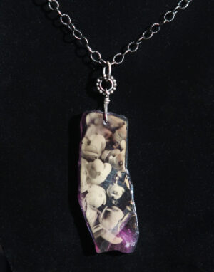A necklace with a purple and white stone on it.