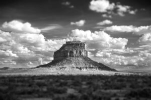 A black and white photo of a mountain with clouds in the background.