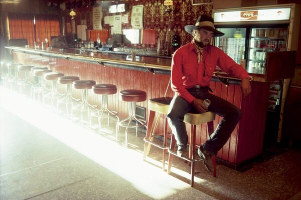A man sitting on top of a stool in front of a bar.