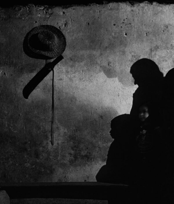 A person with a hat and umbrella in the dark.