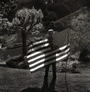 A person holding an american flag in the dark.