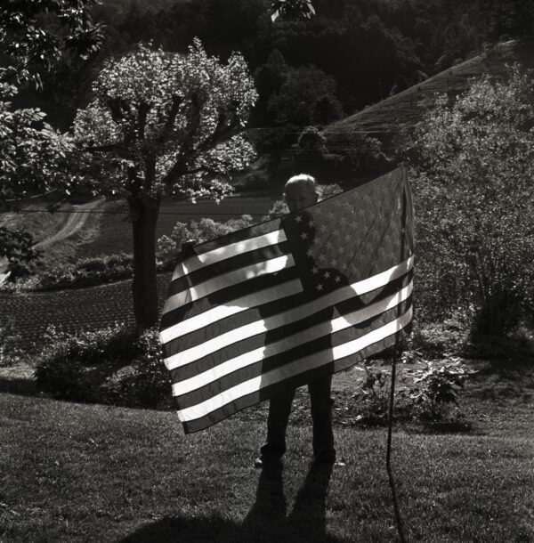 A person holding an american flag in the dark.