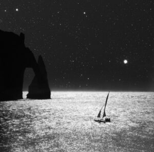 A boat in the ocean at night with an arch.