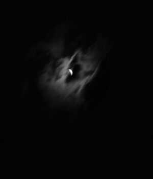 A black and white photo of the moon in the dark.