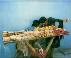 A couple of people standing next to some food.