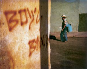 A person walking in front of a wall with graffiti on it.