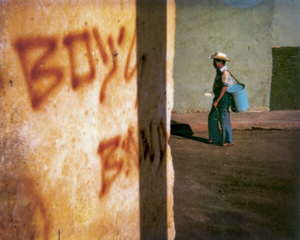 A person walking in front of a wall with graffiti on it.