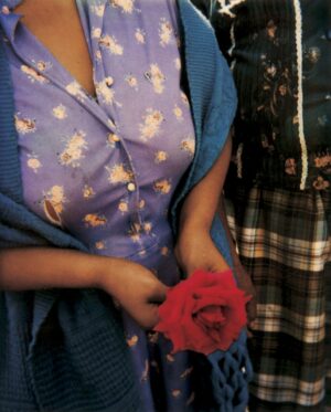 A woman holding a red rose in her hand.