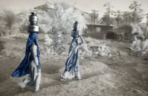 Two people in blue robes holding water containers.