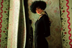 A woman in black outfit and afro wig.