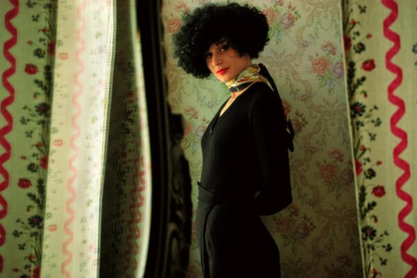 A woman in black outfit and afro wig.