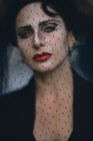 A woman with red lipstick and black polka dot veil.