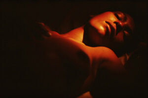 A person laying in the dark with their arms crossed.
