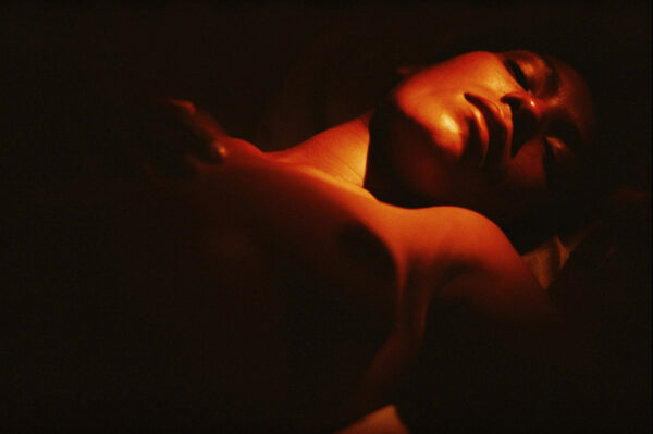 A person laying in the dark with their arms crossed.